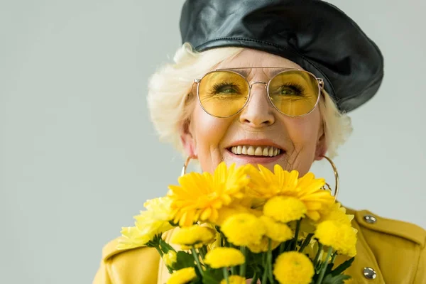 Mujer mayor con flores amarillas - foto de stock