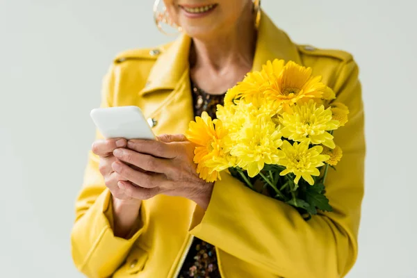 Mulher sênior com flores e smartphone — Fotografia de Stock