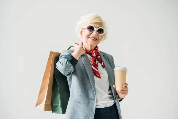 Пожилая женщина с пакетами для покупок и кофе — стоковое фото