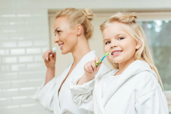 Madre e hija cepillándose los dientes - foto de stock