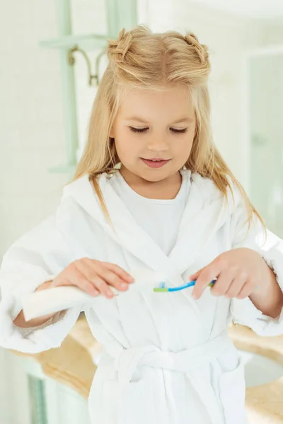 Criança em roupão escovar os dentes — Fotografia de Stock