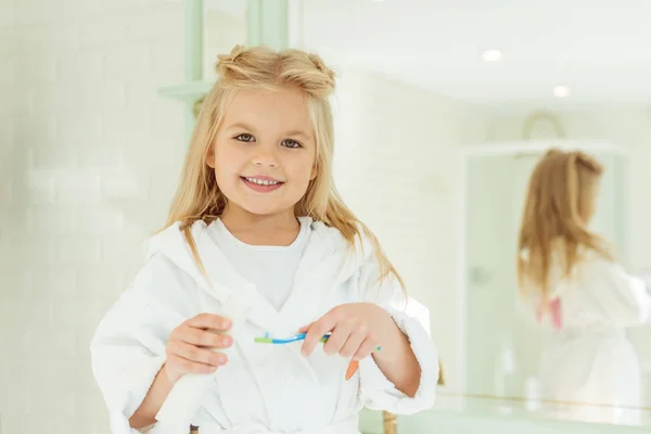 Ребенок в халате чистка зубов — стоковое фото
