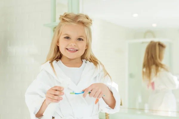 Niño en albornoz cepillarse los dientes - foto de stock