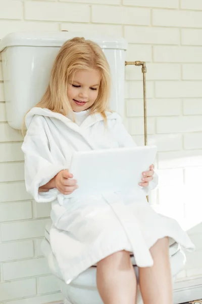 Child with digital tablet on toilet — Stock Photo