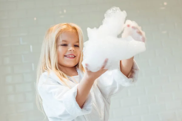 Child playing with foam in bathroom — Stock Photo