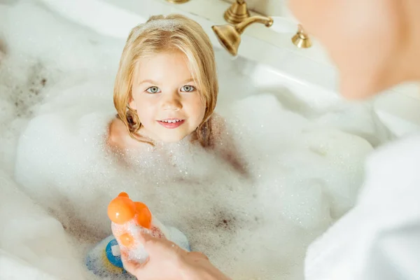 Madre lavando hija en bañera - foto de stock