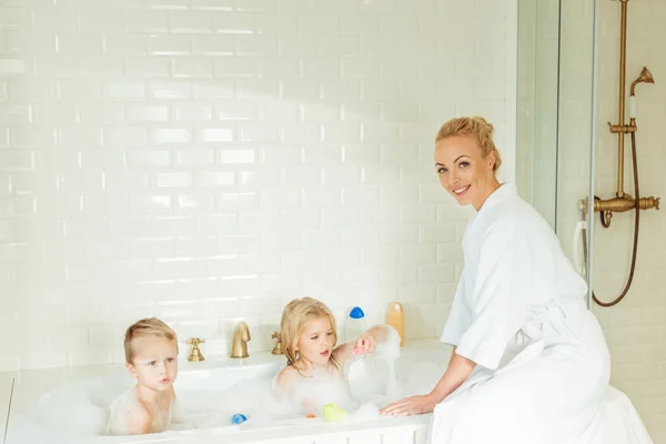 Madre lavando niños en bañera - foto de stock