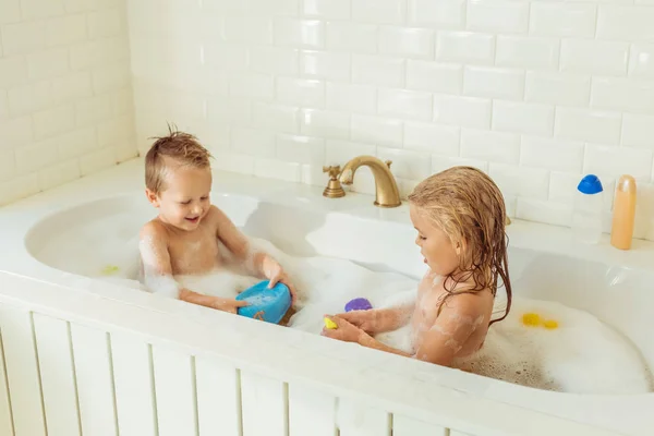 Kids playing in bathtub with foam — Stock Photo