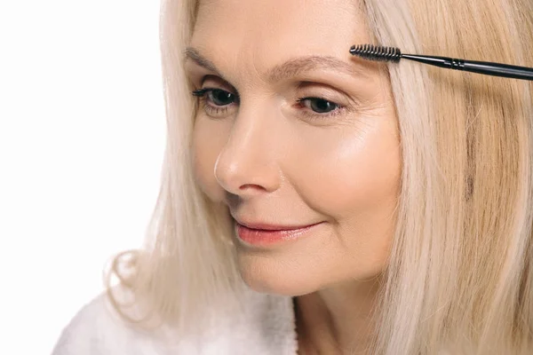 Mujer madura usando cepillo de cejas - foto de stock