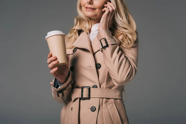 Жінка в траншеї пальто розмовляє по телефону — стокове фото