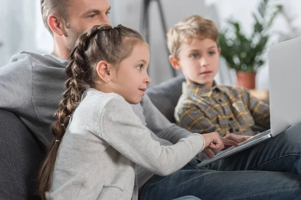 Father sitting with children and laptop — Stock Photo