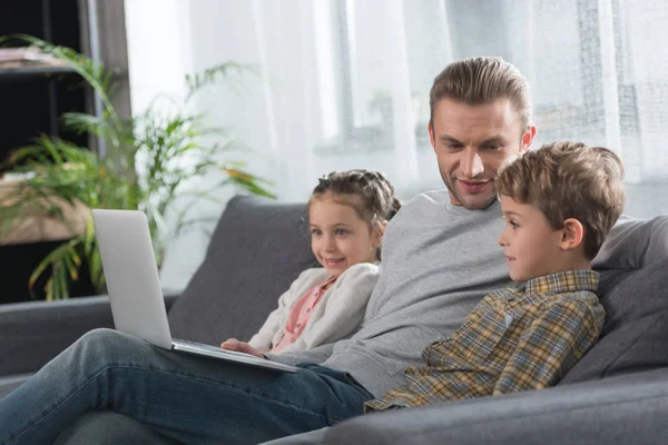 Father sitting with children on sofa — Stock Photo