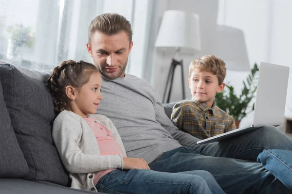 Padre sentado con los niños en el sofá - foto de stock