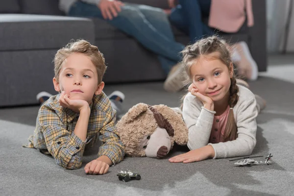 Children lying on floor with toys — Stock Photo