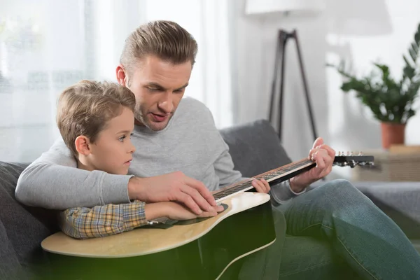 Padre enseñanza hijo jugar guitarra - foto de stock