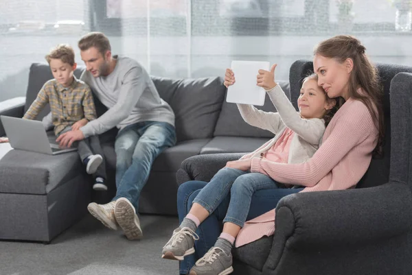 Familia en el sofá usando gadgets - foto de stock