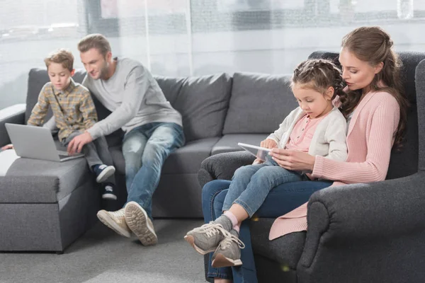 Familia con niños usando aparatos en el sofá - foto de stock