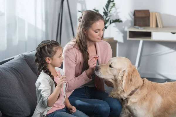 Mère et fille caressant chien — Photo de stock