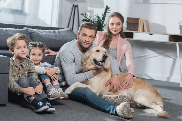 Famiglia e cane seduti al piano — Foto stock