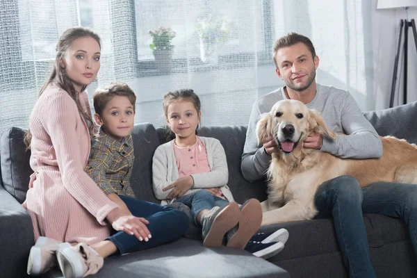 Family petting dog on couch — Stock Photo