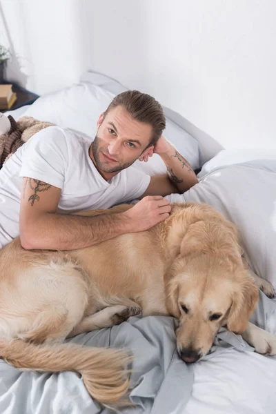 Homem deitado na cama com o cão — Fotografia de Stock