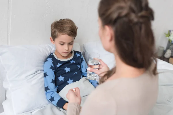 Mother giving medicine to son — Stock Photo