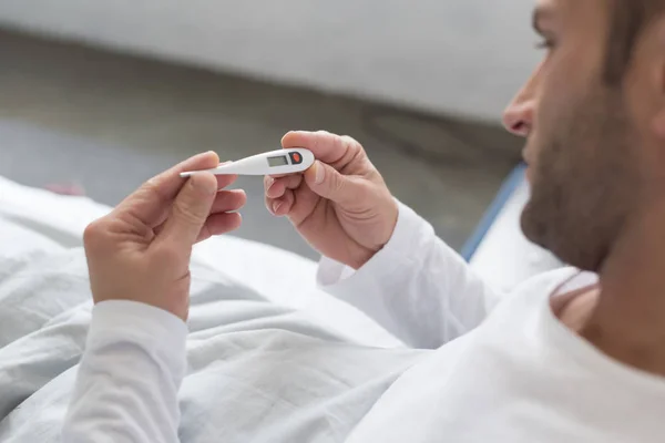 Sick Man looking at thermometer — Stock Photo