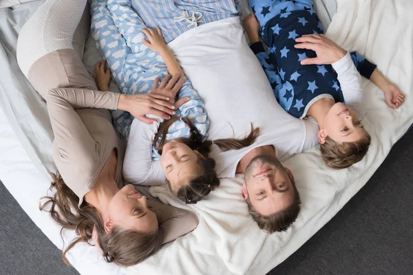 Famiglia con bambini sdraiati sul letto — Foto stock