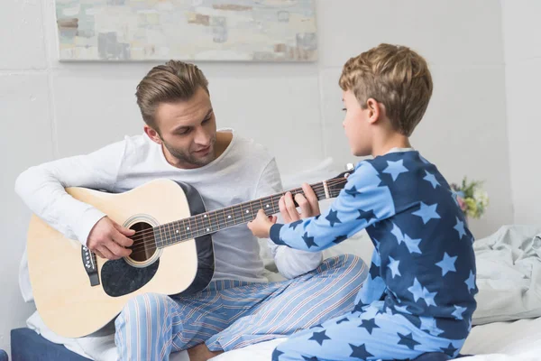 Padre mostrando hijo cómo tocar la guitarra - foto de stock