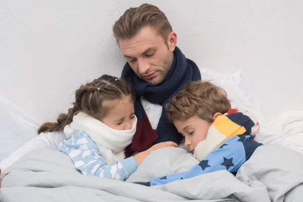 Padre enfermo con hijo e hija en la cama - foto de stock