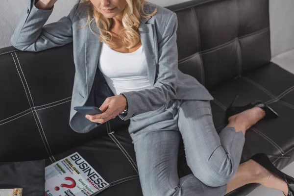 Donna d'affari che utilizza smatphone sul divano — Foto stock