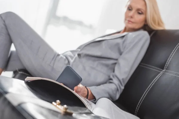 Бізнес-леді, використовуючи смартфон на дивані — стокове фото