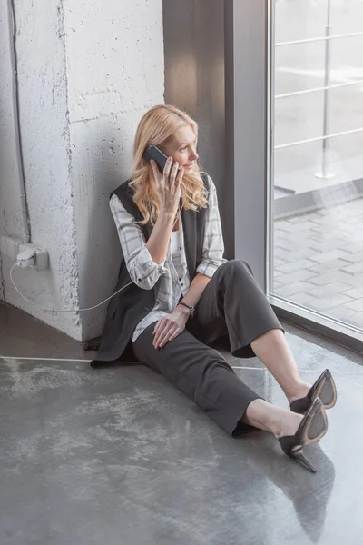 Geschäftsfrau lädt Smartphone und telefoniert — Stockfoto