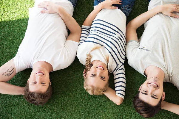 Young friends lying on grass — Stock Photo