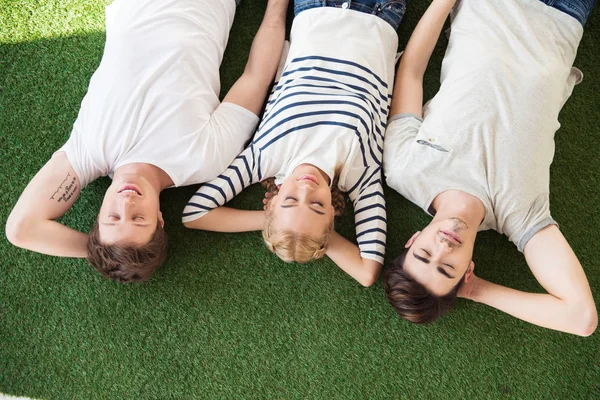 Jovens amigos deitados na grama — Fotografia de Stock