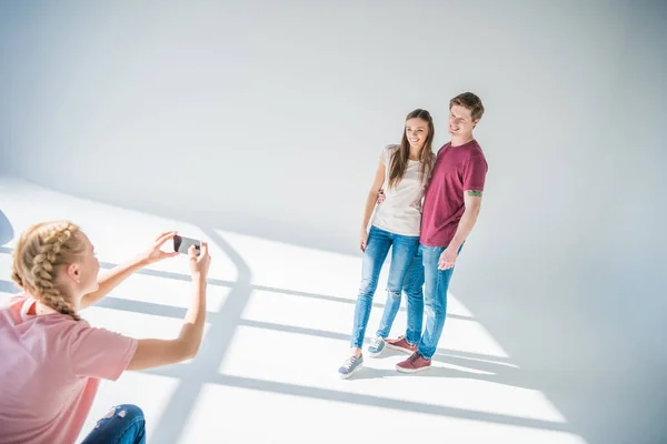 Девушка фотографирует пару со смартфоном — стоковое фото