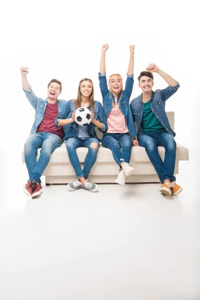 Amigos con pelota de fútbol sentado en el sofá - foto de stock