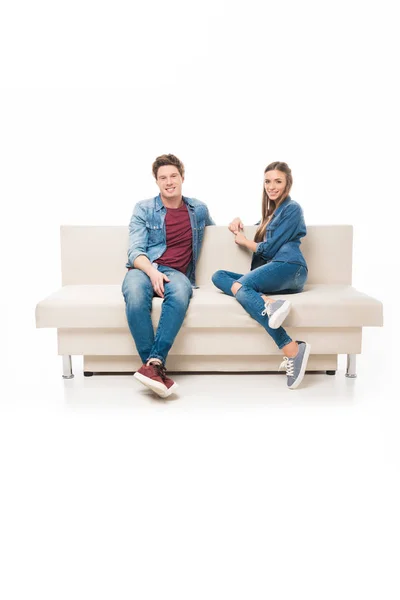 Joven pareja sentado en sofá - foto de stock