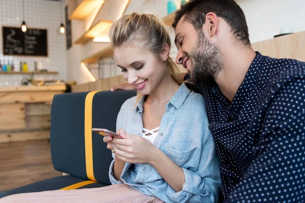 Молодая пара со смартфоном в кафе — стоковое фото