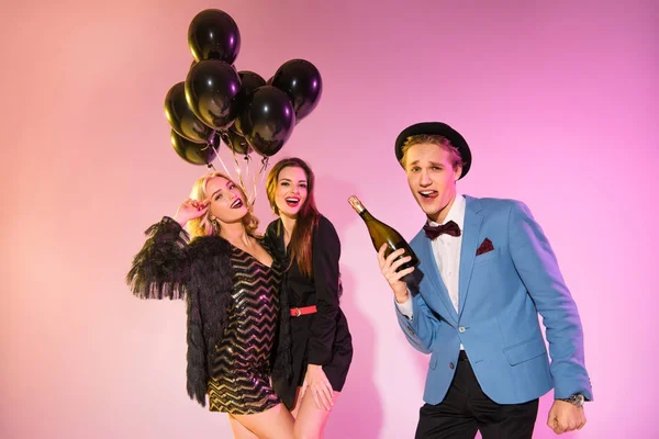 Friends with champagne and black balloons — Stock Photo
