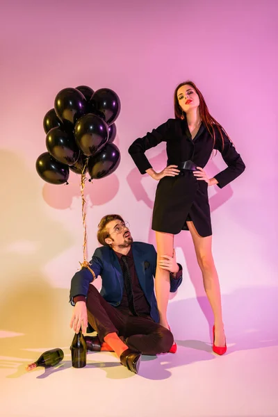 Paar mit Champagnerflaschen und schwarzen Luftballons — Stockfoto