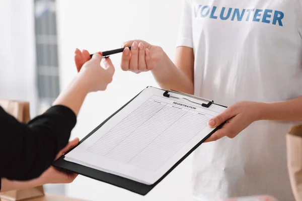 Voluntario dando formulario de inscripción a la mujer - foto de stock