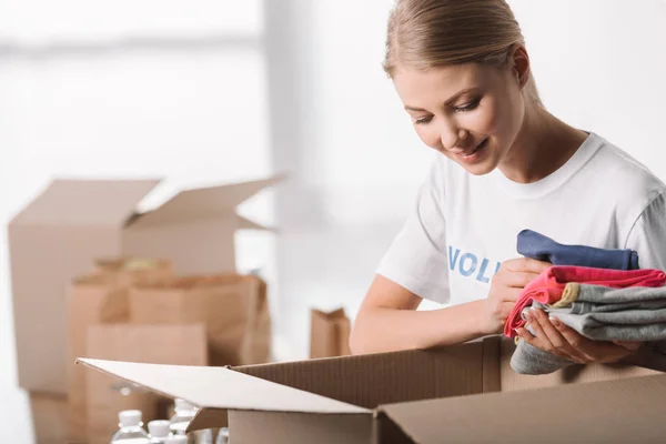 Bénévole femelle mettre des vêtements dans la boîte — Photo de stock