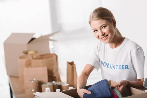 Voluntária feminina colocando roupas na caixa — Fotografia de Stock