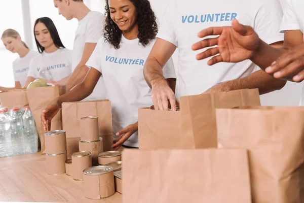 Freiwillige packen Essen und Getränke in Säcke — Stockfoto