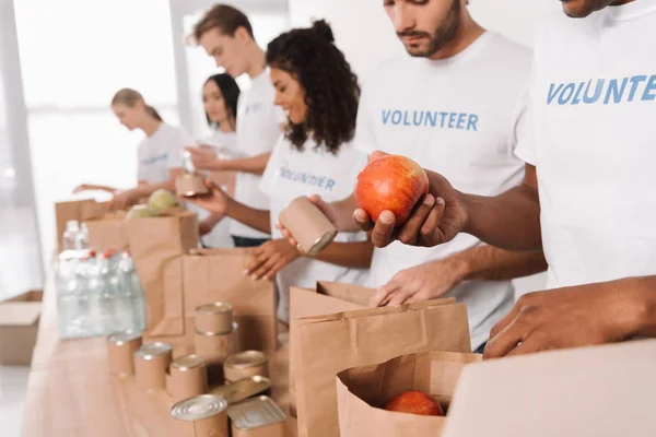 Voluntarios poniendo comida y bebidas en bolsas - foto de stock