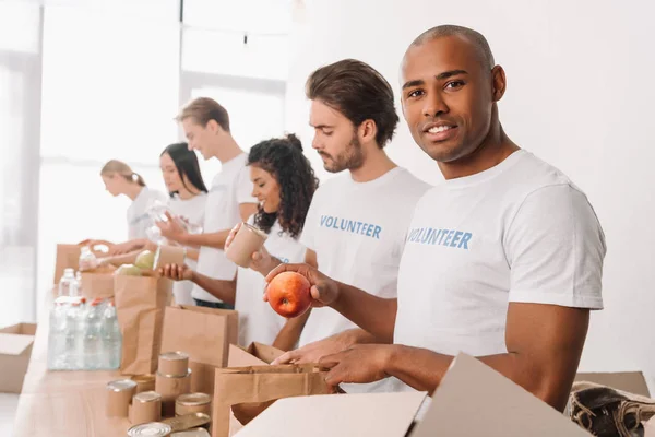 Volunteer packing food into bag — Stock Photo