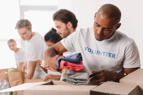 Voluntário colocando roupas na caixa — Fotografia de Stock