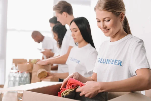 Voluntário colocando roupas na caixa — Fotografia de Stock