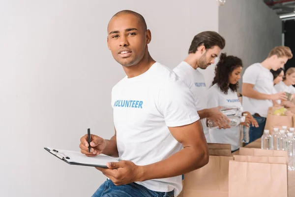 Voluntario afroamericano con portapapeles - foto de stock